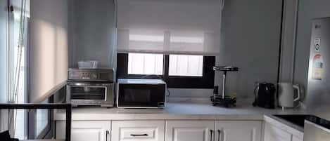 A modern kitchen with white cabinets, a microwave, toaster, and a coffee maker.
