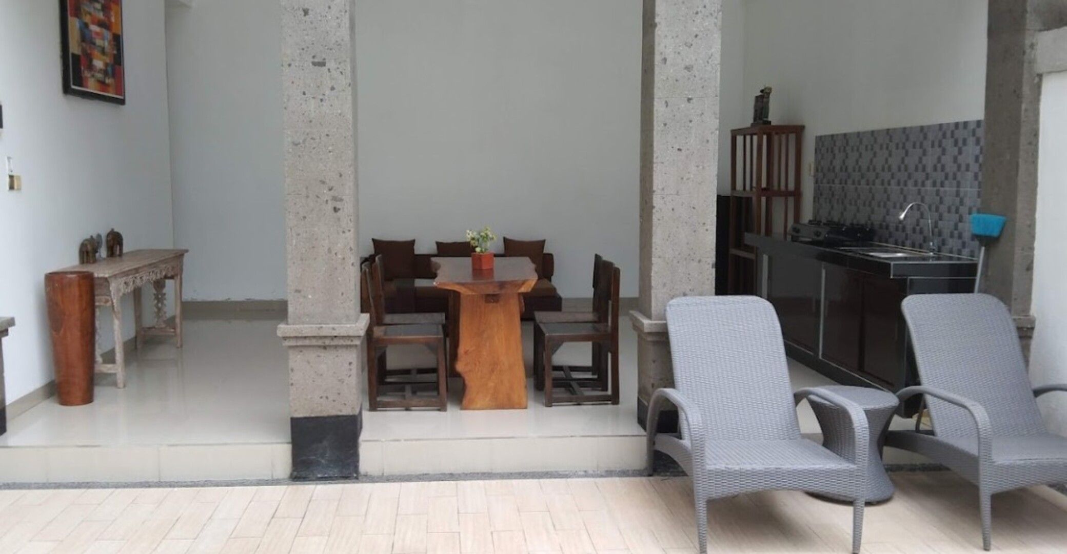 A dining area with a wooden table and chairs, a kitchen area with a counter and appliances, and a tiled floor.