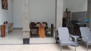 A dining area with a wooden table and chairs, a kitchen area with a counter and appliances, and a tiled floor.