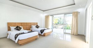 Ein Hotelzimmer mit zwei Betten, einem Balkon und einem großen Fenster.