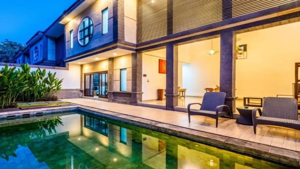 A modern house with a swimming pool, outdoor seating, and a large window overlooking the pool. - Cozzy Fullmoon Purnama Villa Ubud (Gianyar)
