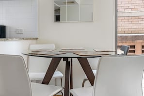 A round table with a dark wooden base surrounded by white chairs. - Private flat, spacious and central in Sydney (Sydney)