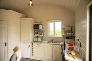 Eine kompakte Küche mit Spüle, Mikrowelle und Toaster. Ein Fenster sorgt für natürliches Licht.