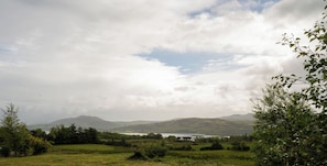 Ländliche Landschaft mit einem See, Bergen und einer kleinen Häusergruppe.