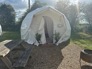 Una tenda amb un estenedor i una banca de fusta a l'exterior.