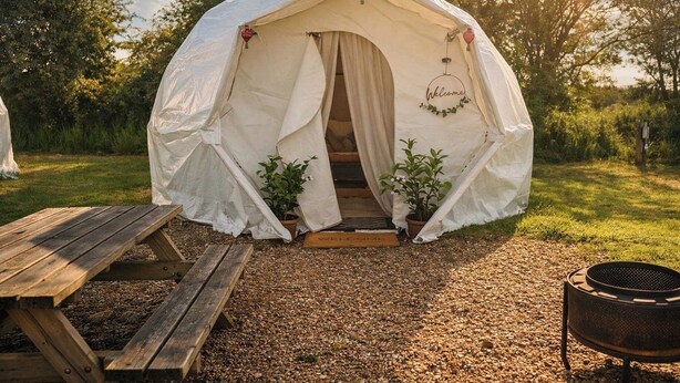 A tent with a door, two potted plants, a wooden bench, and a grill. - The Leaf & Lantern Dome - Sleeps 5 - Dog Friendly (Pewsey)