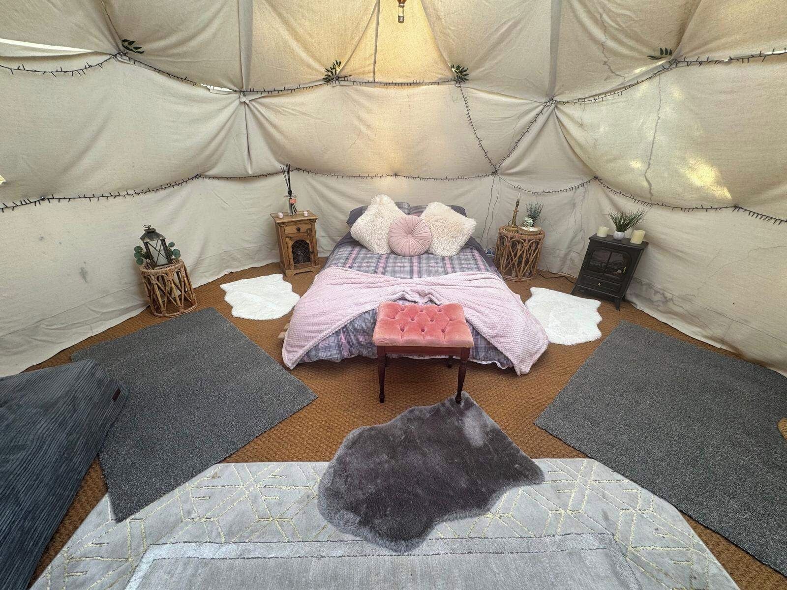 Een gezellig interieur met een bed, kussens, een bankje en decoratieve objecten.
