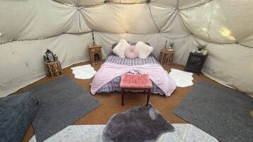 Een gezellig interieur met een bed, kussens, een bankje en decoratieve objecten.