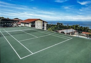 An outdoor tennis court with a clear view of the ocean and a building in the background. - 2/2 2 King Beds, 2  Inflatable  SUP, Clubs, Washer Dryer, Ocean View! Sunsets! (Holualoa)
