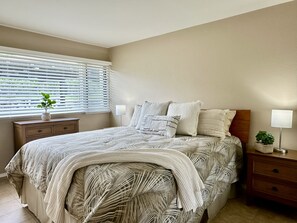 A bedroom with a bed, bedside tables, a window with blinds, and a plant. - 2/2 2 King Beds, 2  Inflatable  SUP, Clubs, Washer Dryer, Ocean View! Sunsets! (Holualoa)