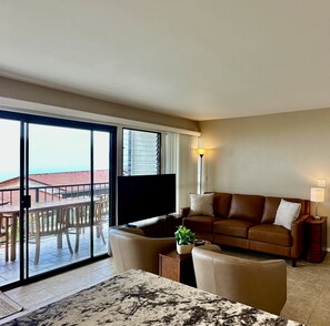 Living room overlooking the lanai with glimpse of the blue Pacific Ocean.