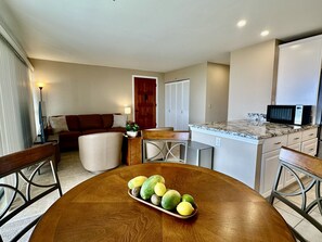 A compact living space with a dining table, a kitchen area, a seating area, and a door leading to a closet.