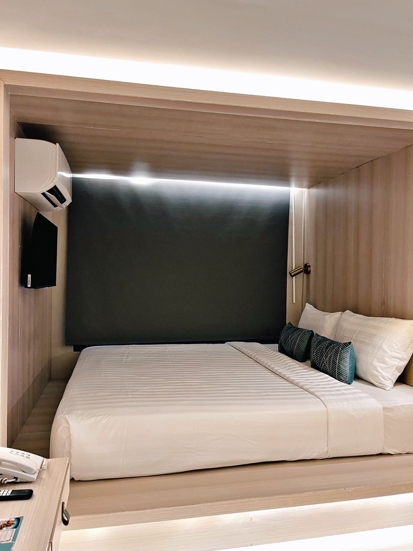 Un dormitorio moderno con una cama grande, una mesita de noche, un aire acondicionado de pared y una puerta con picaporte.