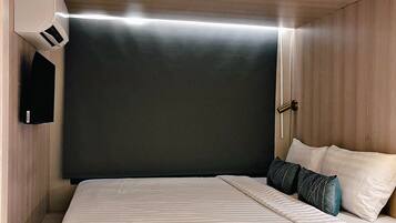 Un dormitorio moderno con una cama grande, una mesita de noche, un aire acondicionado de pared y una puerta con picaporte.