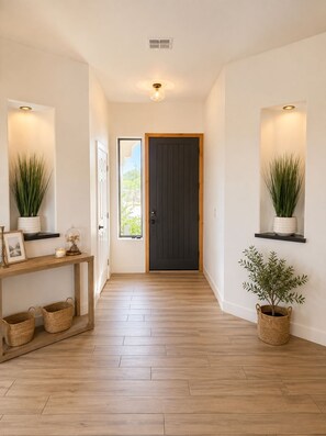 A hallway with a wooden floor, a dark door, and two wall-mounted plants. - New! Luxury Private Desert Retreat + 4 Beds + Hot Tub + Gated + 5 Horse Stalls (Scottsdale)