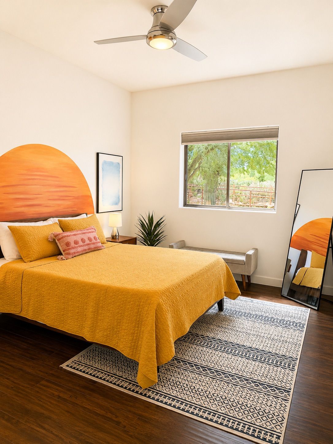 A bedroom with a bed, a ceiling fan, a window, and a mirror.