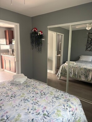 Een slaapkamer met een bed, een spiegel en uitzicht op een badkamer.