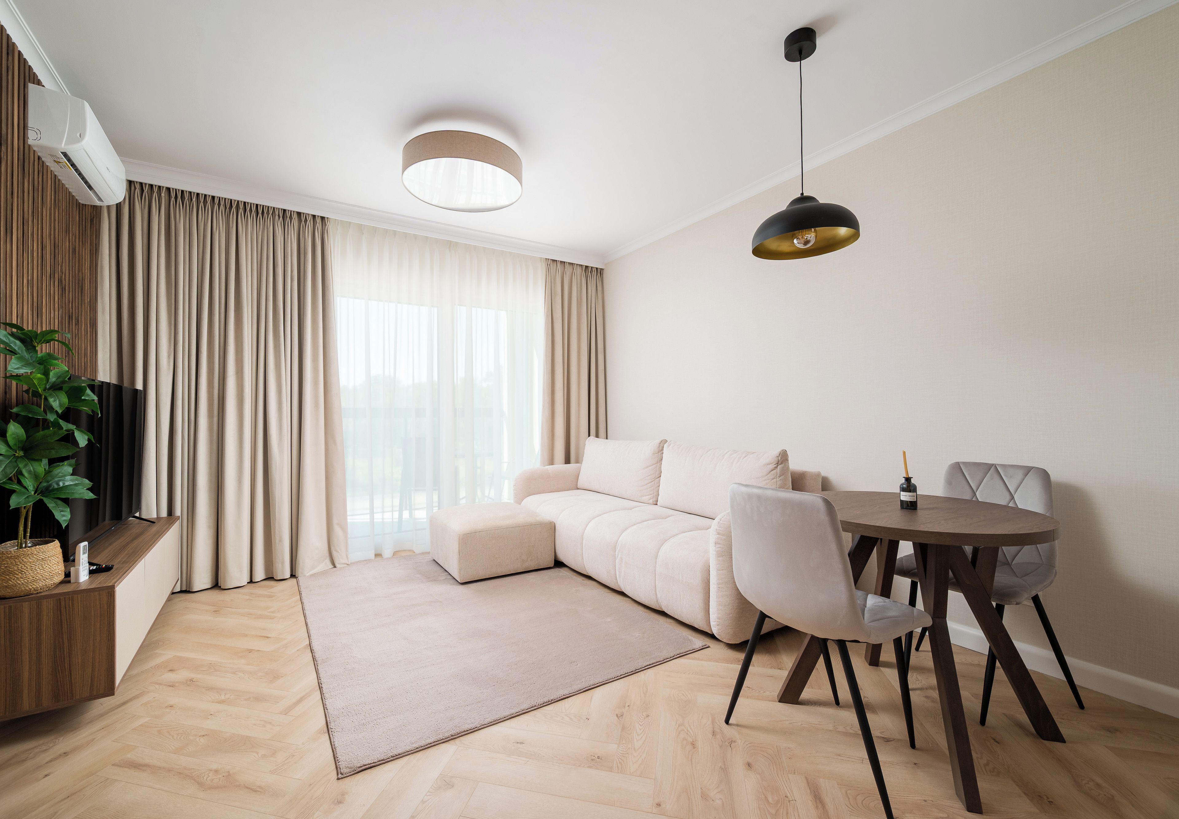 Ein stilvolles Wohnzimmer mit einer Couch, einem Esstisch und einer Hängeleuchte.
