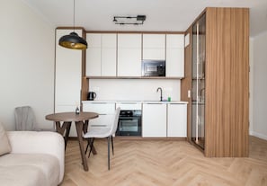 A compact kitchen with a dining area, a built-in oven, and a modern pendant light. - Lotnisko Chopina Luxury Apartment (Warszawa)