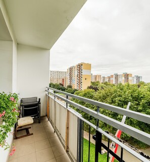 A balcony with a chair, a small table, and a potted plant. - Grunwald Standard Apartment (Poznań)