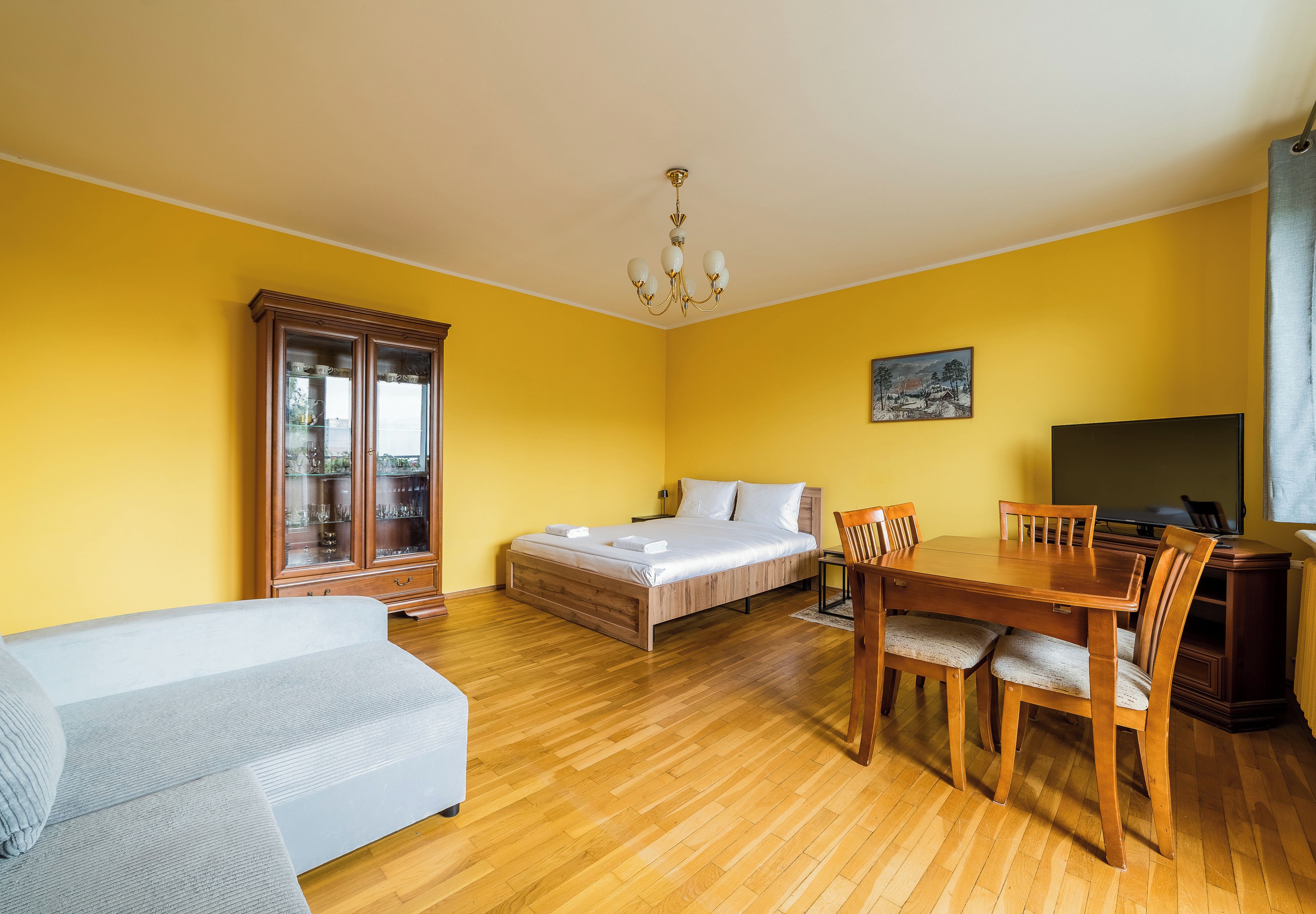 Una habitación con una cama, una mesa de comedor con sillas, un sofá y un armario.