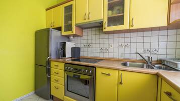 Une cuisine avec des meubles de couleur jaune, un réfrigérateur en acier inoxydable, un four encastré et un évier.