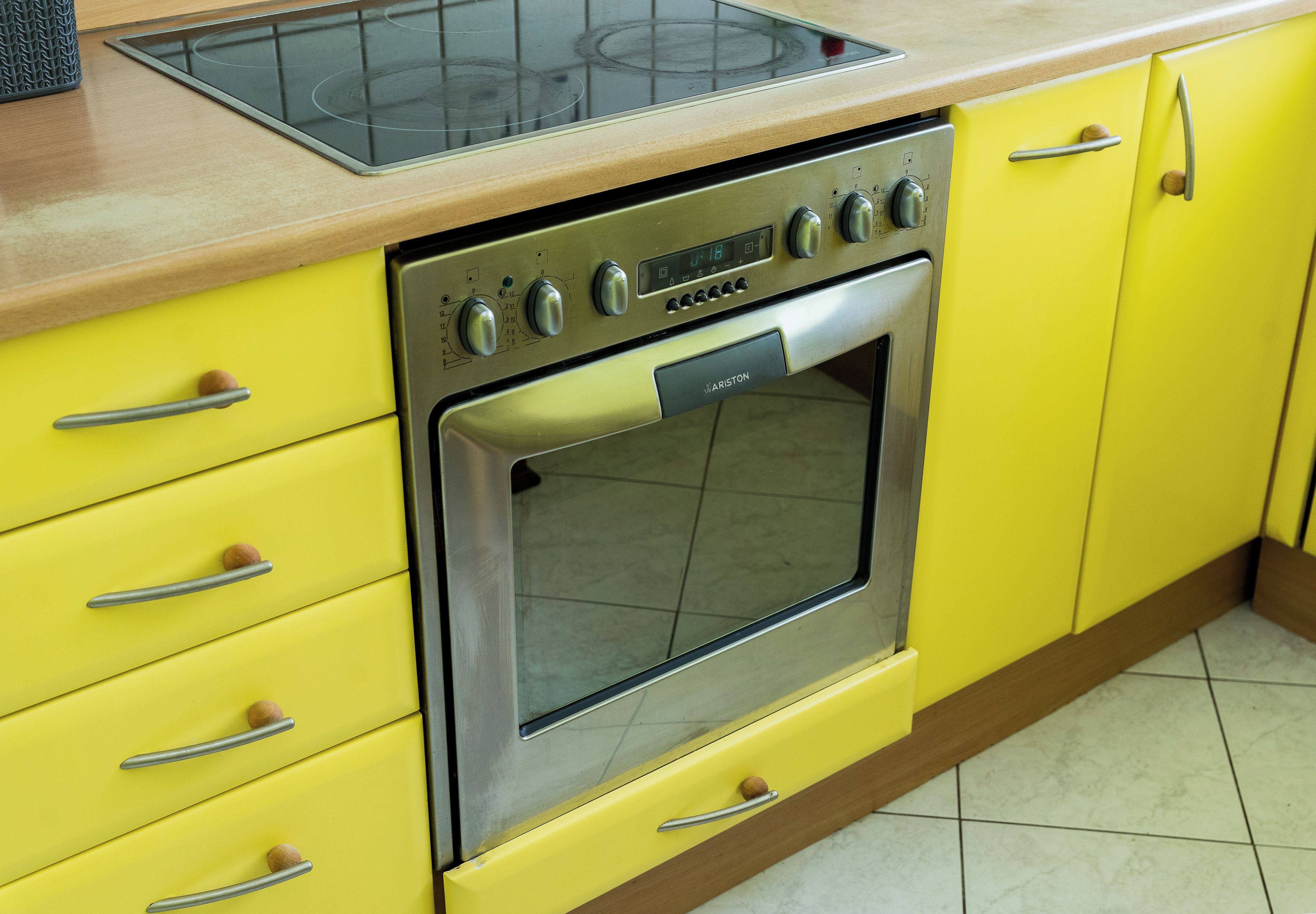 Una cocina con estufa de acero inoxidable, armarios amarillos y encimera de madera.
