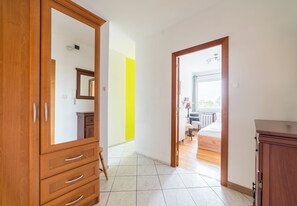 A hotel room with a wooden wardrobe, a mirror, a bed, and a view of the outside. - Grunwald Standard Apartment (Poznań)