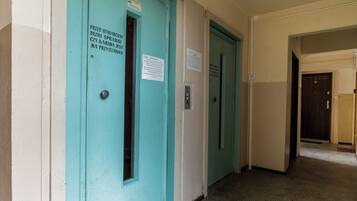 A corridor with teal doors, each marked with a sign indicating the room number.
