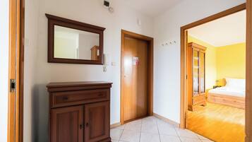 A room with a wooden wardrobe, a door with a sign, and a bed in the adjacent room.