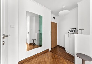 Ein Korridor mit Holzboden, weißen Wänden, einer grünen Tür und einer weißen Decke mit einer Leuchte.