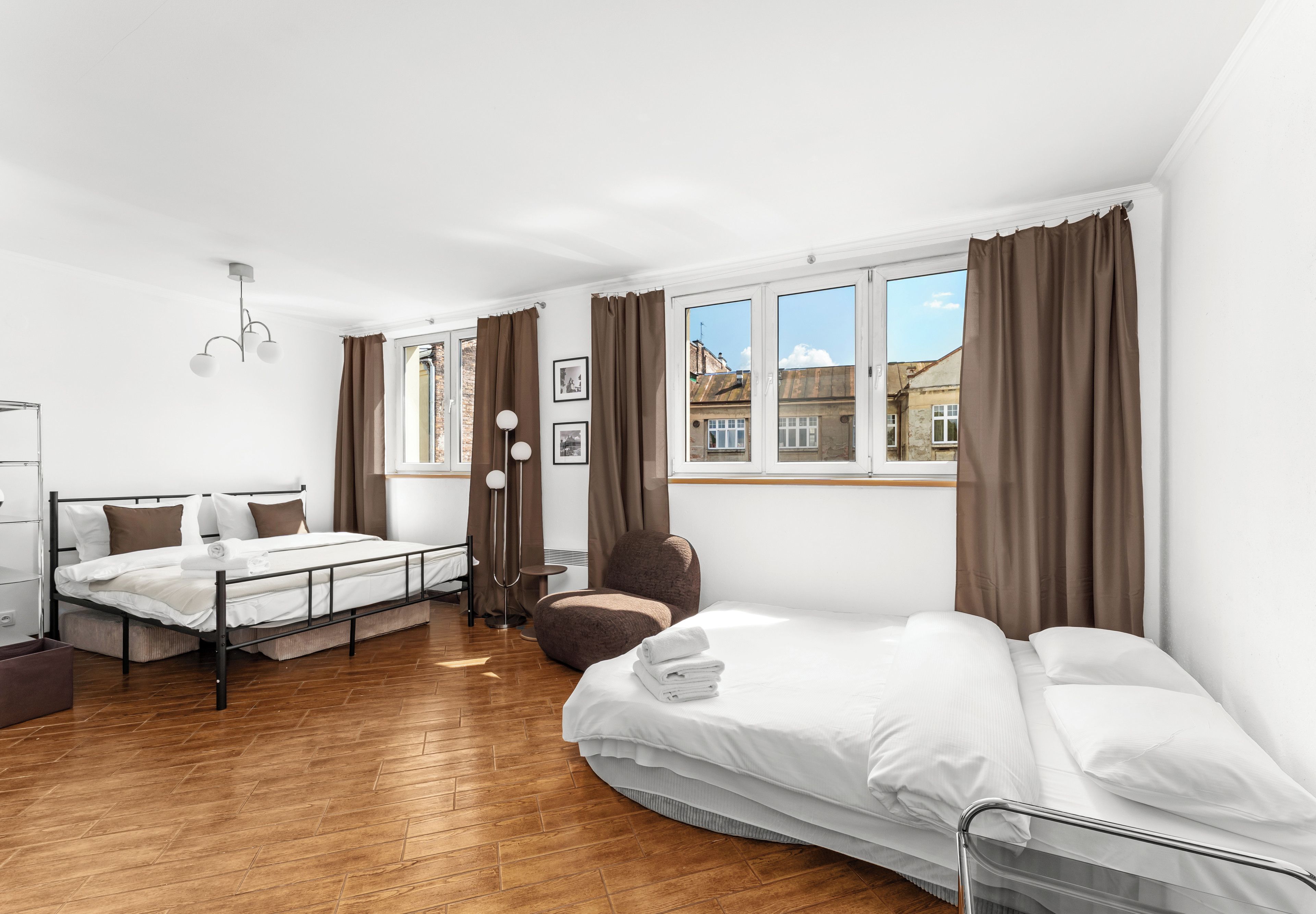 A hotel room with a bed, a chair, a desk, and a window with curtains.