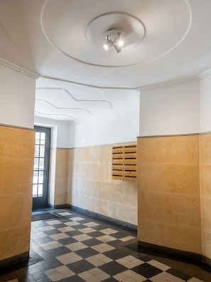 A hallway with checkered flooring, a ceiling with recessed lighting, and a door at the end. - Garbarska Old Town Cream Apartment (Kraków)