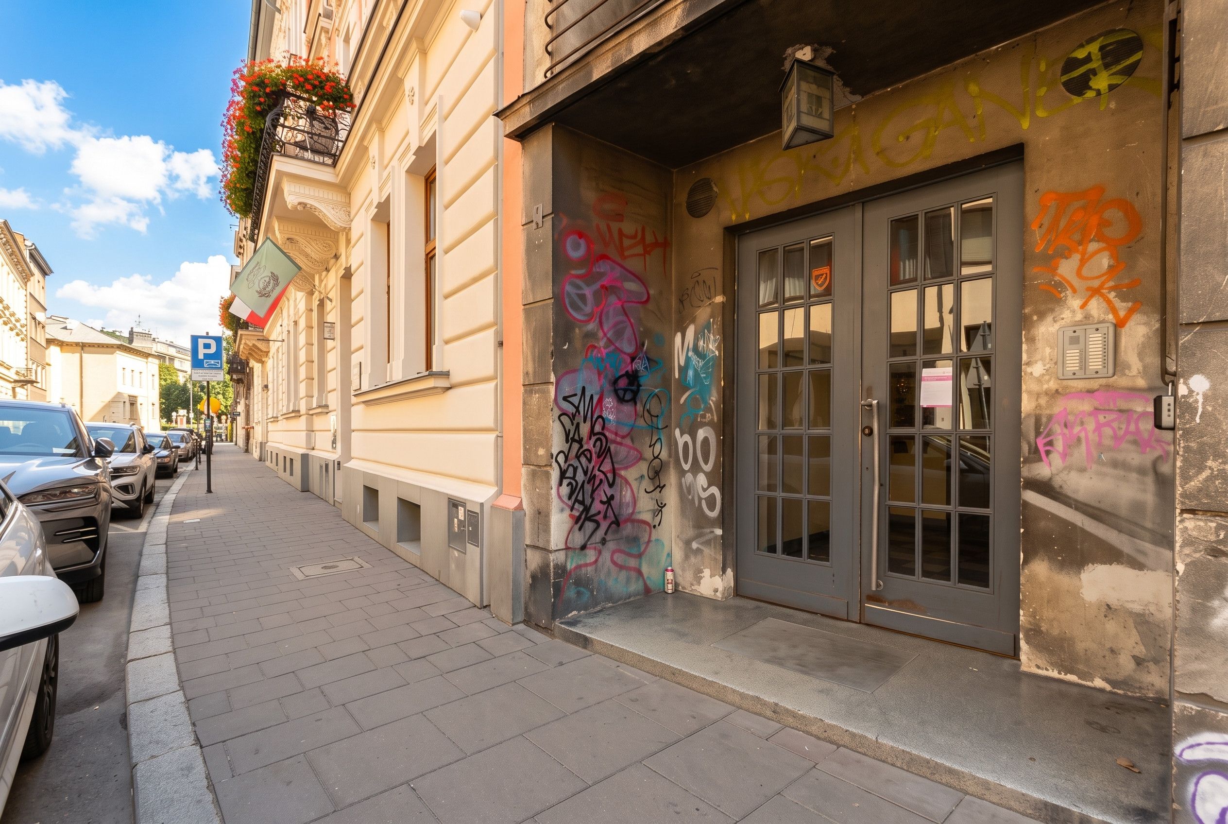 Una calle con coches aparcados y un edificio con grafitis.
