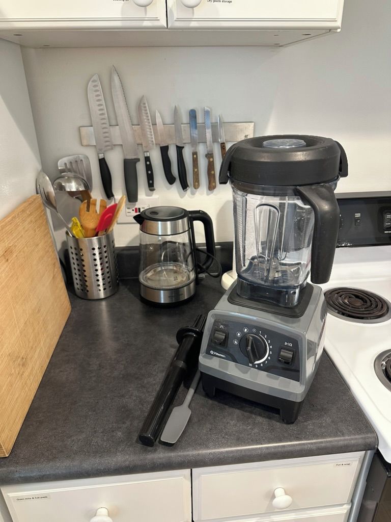 Una cocina con batidora, cuchillos y cafetera.