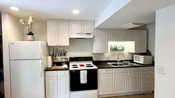 A modern kitchen with white cabinetry, a black stove, and a microwave.