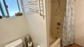 Un baño con inodoro, ducha, toallero y ventana.