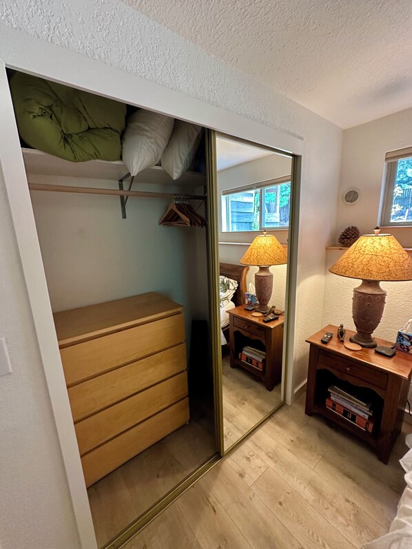 A bedroom with a bed, a dresser, a mirror, a nightstand, and a lamp.