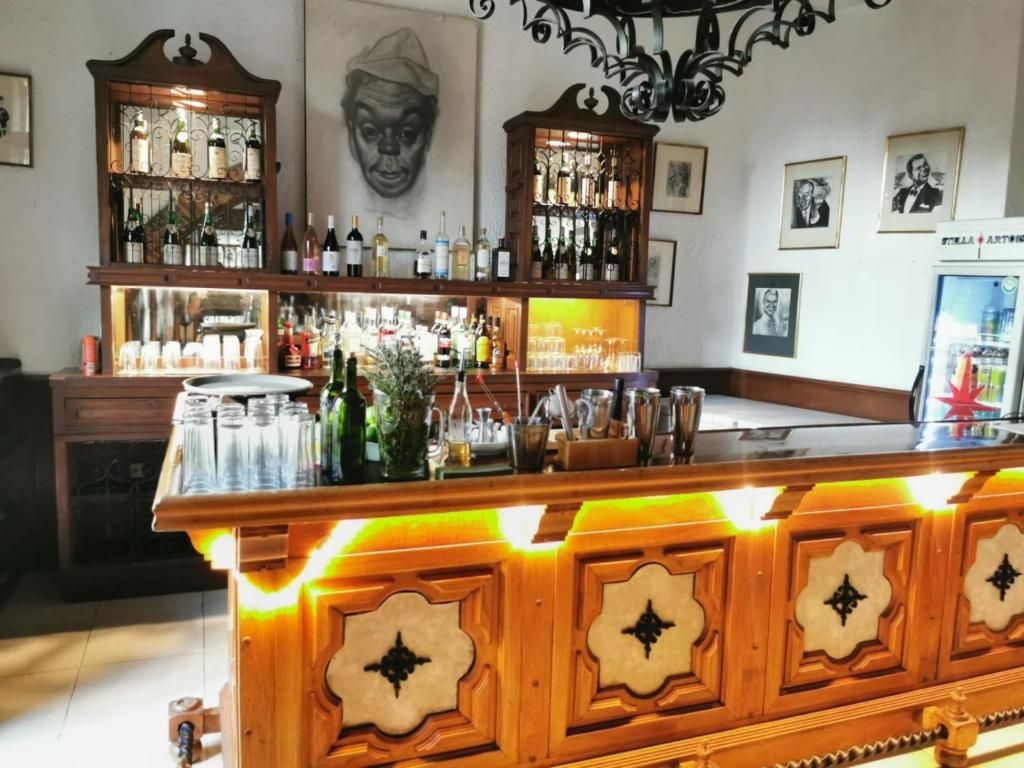 Una zona de bar con armarios y estantes de madera que exhiben botellas y vasos.