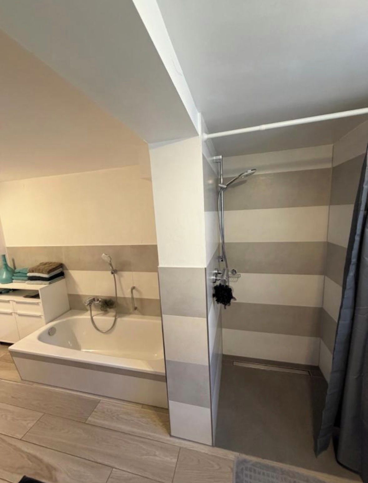 A bathroom with a bathtub, a shower, and a towel rack.
