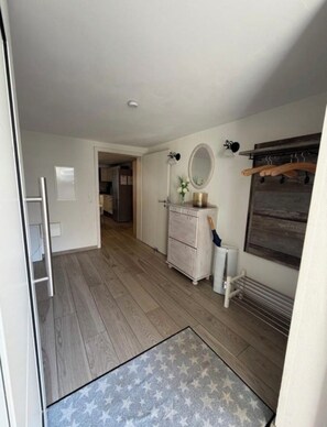 A hallway with a wooden floor, a white dresser with a mirror, a radiator, and a coat rack. - Quaint 1-bedroom house in charming Linsengericht perfect for getaway (Linsengericht)