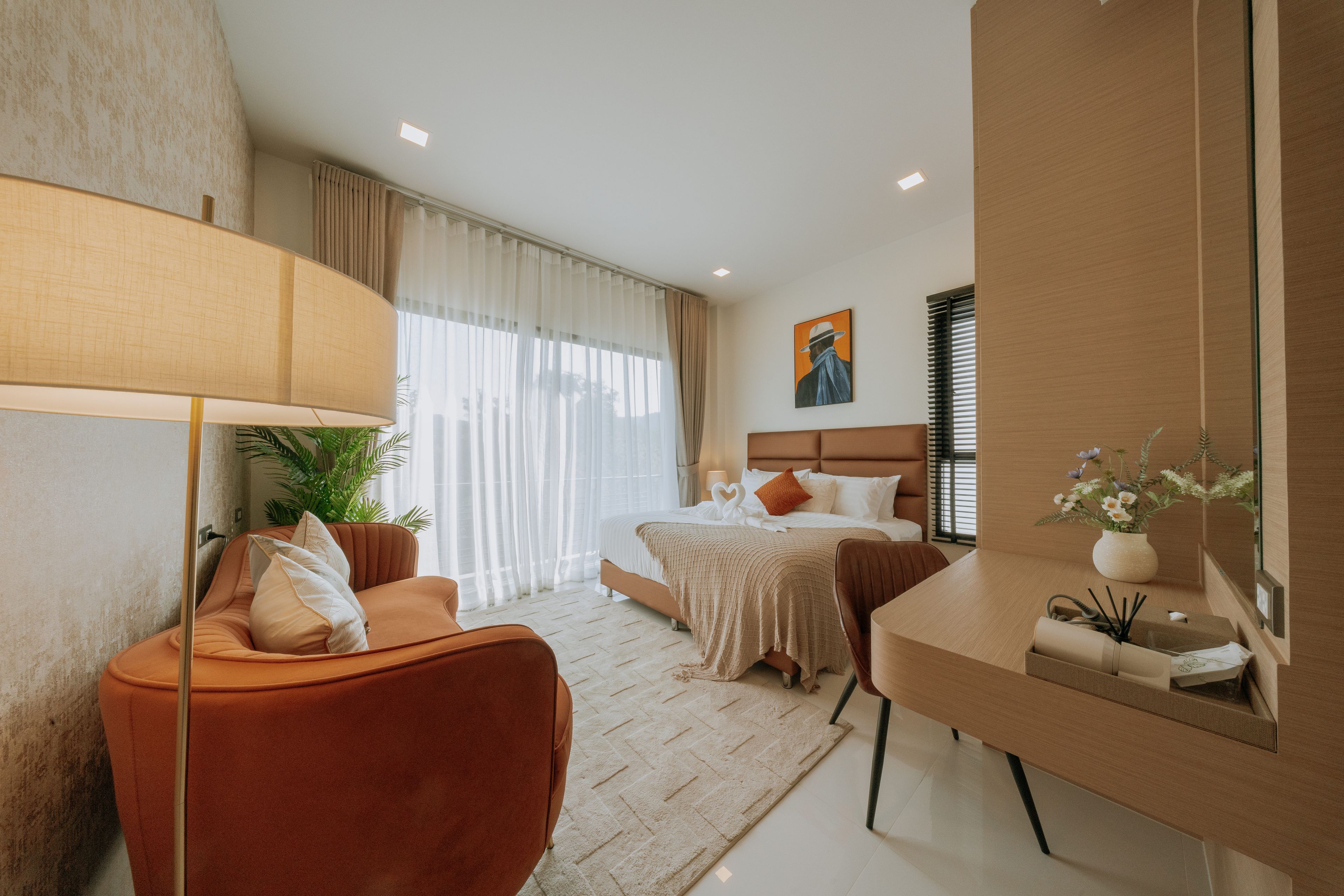 A modern hotel room with a sofa, a bed, a desk, and a large window.