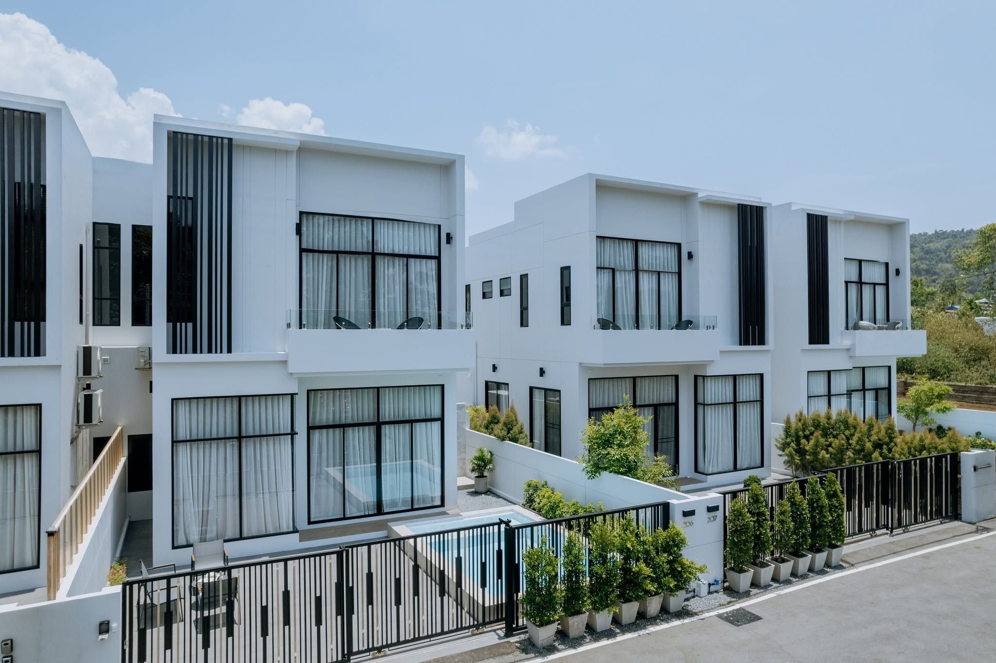 Un edificio residencial moderno con varios balcones, grandes ventanales y un jardín bien cuidado.