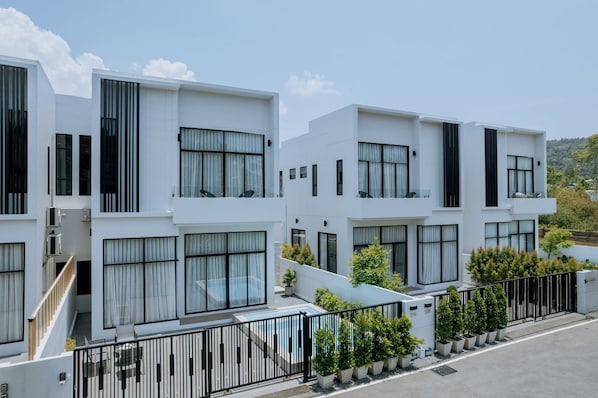 Un edificio residencial moderno con varios balcones, grandes ventanales y un jardín bien cuidado.