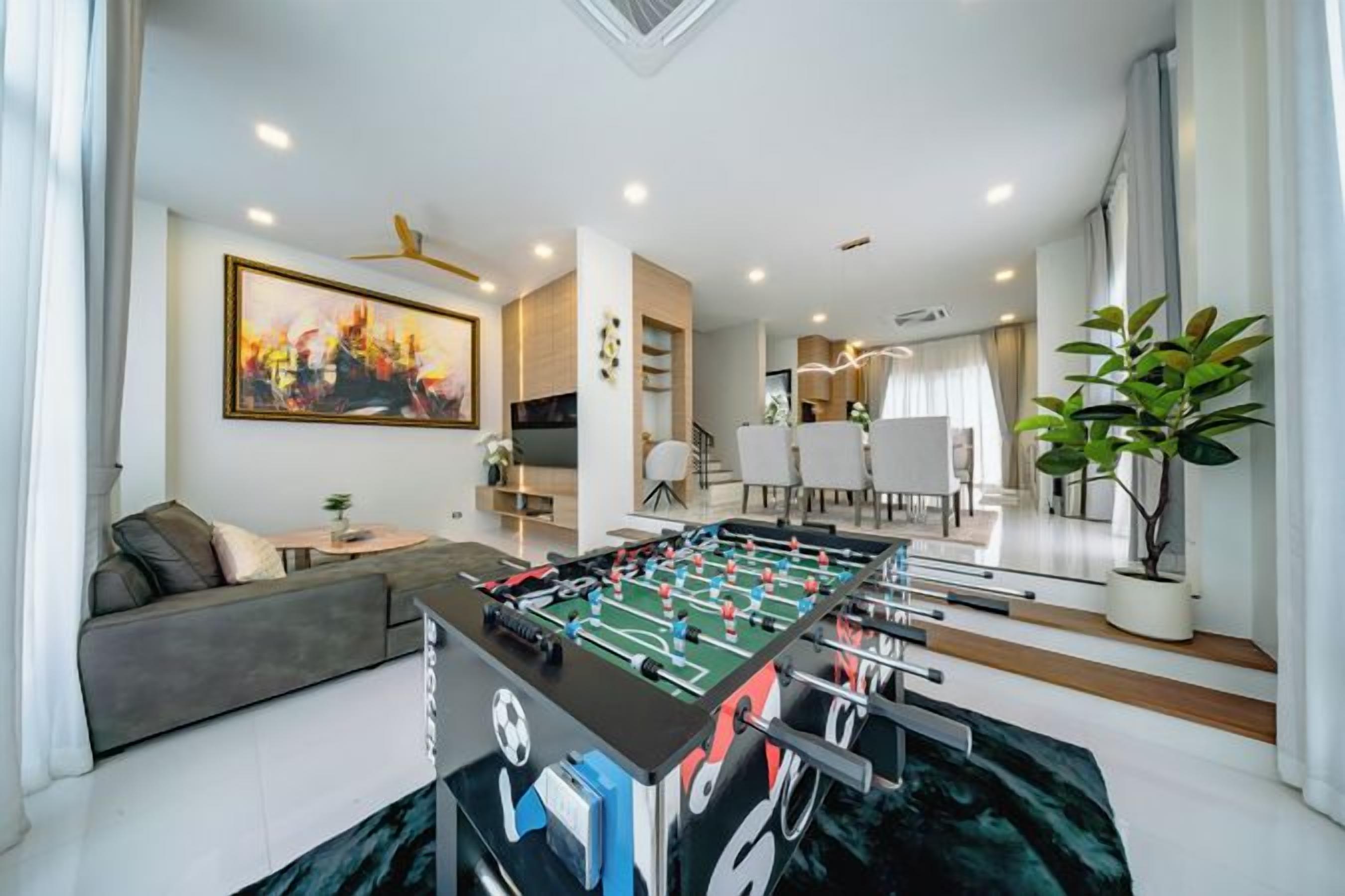 A modern living room with a foosball table, a sofa, and a dining area.