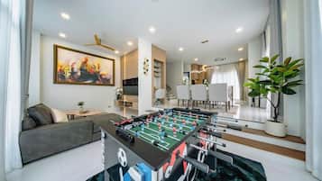 A modern living room with a foosball table, a sofa, and a dining area.