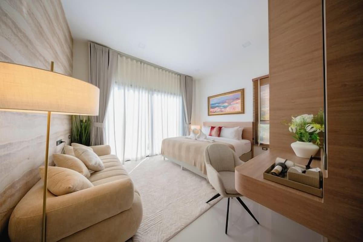 Habitación de hotel con sofá, escritorio, cama, lámpara y un cuadro en la pared.