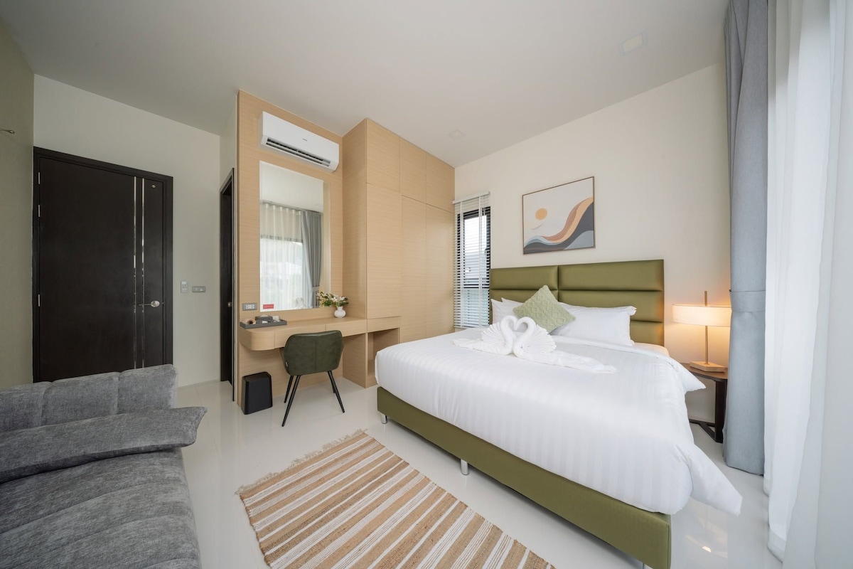 Una habitación de hotel con cama, escritorio, silla, armario y un cuadro en la pared.