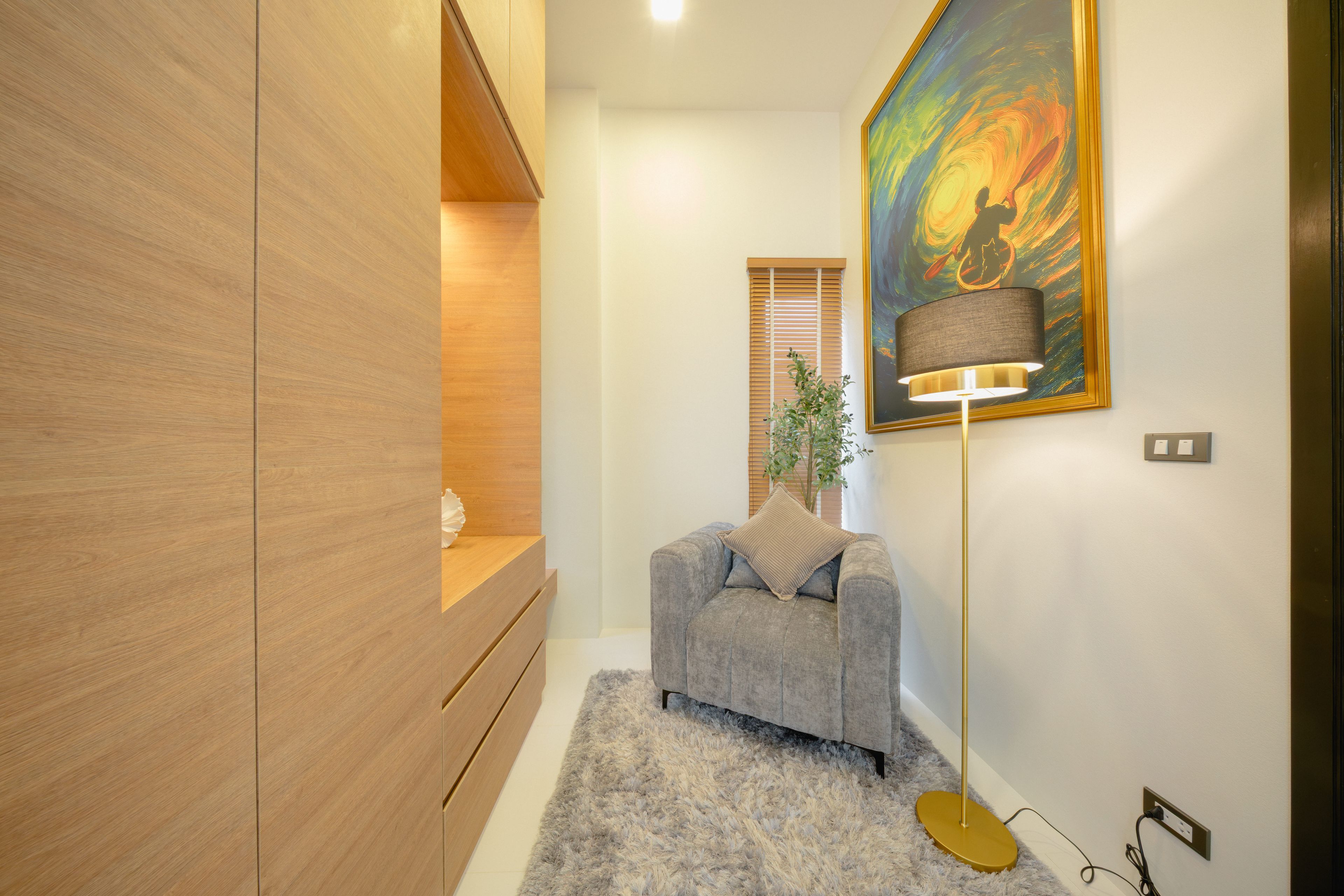 Un interior moderno con un sofá gris, un mueble de madera, un cuadro y una lámpara de pie.