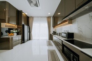 Una cocina moderna con electrodomésticos de acero inoxidable, encimera de mármol y una isla central.